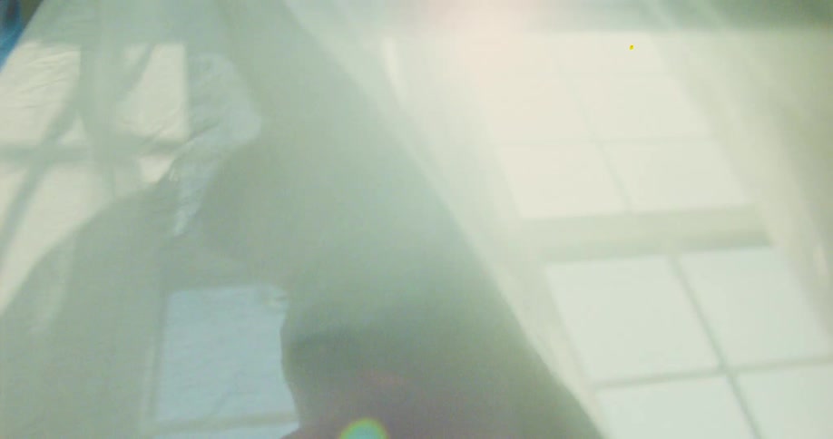 Two kids curl up in a curtain as they spin around with sunlight reflecting through the window