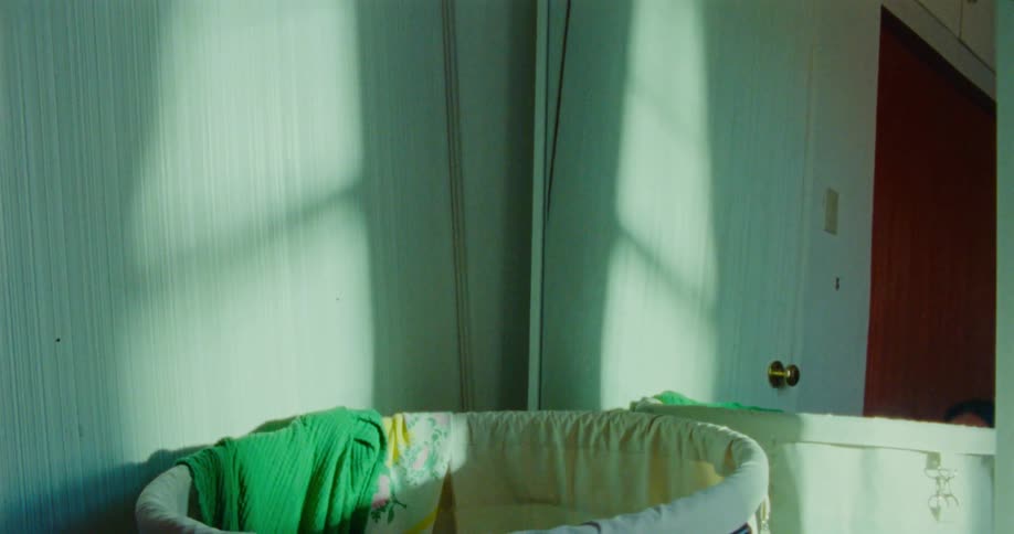 A young male child plays by hiding inside a laundry basket positioned beside a mirror
