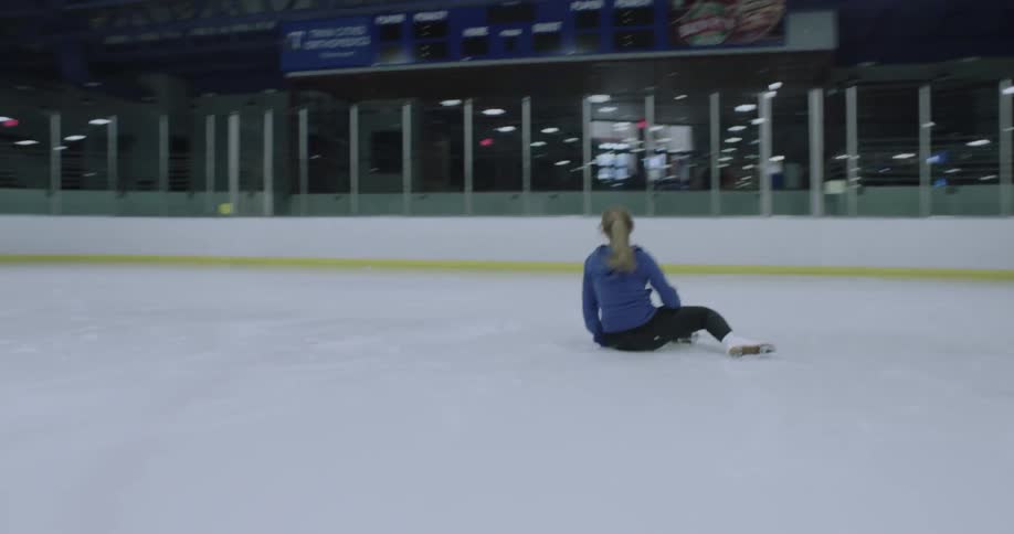 A figure skater practicing a jump falls on the ice