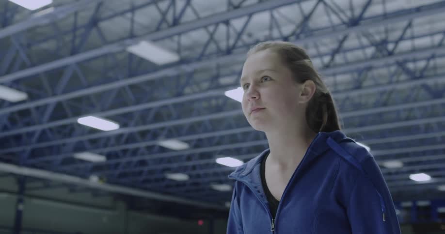 A girl skates on an indoor ice skating rink