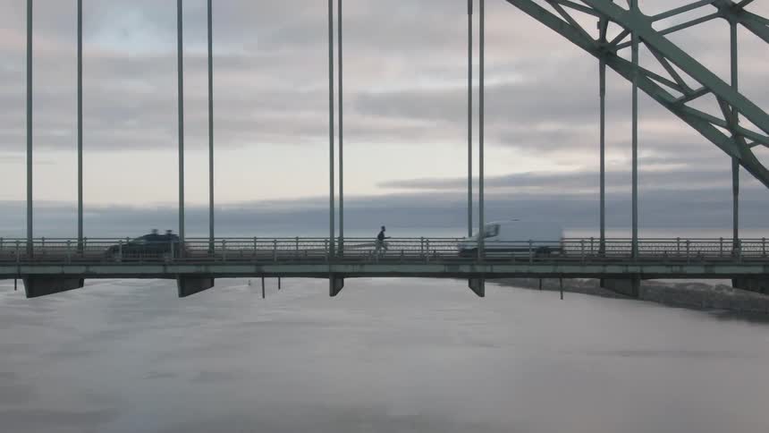 Vehicles passing on a suspension bridge over the sea and a person running