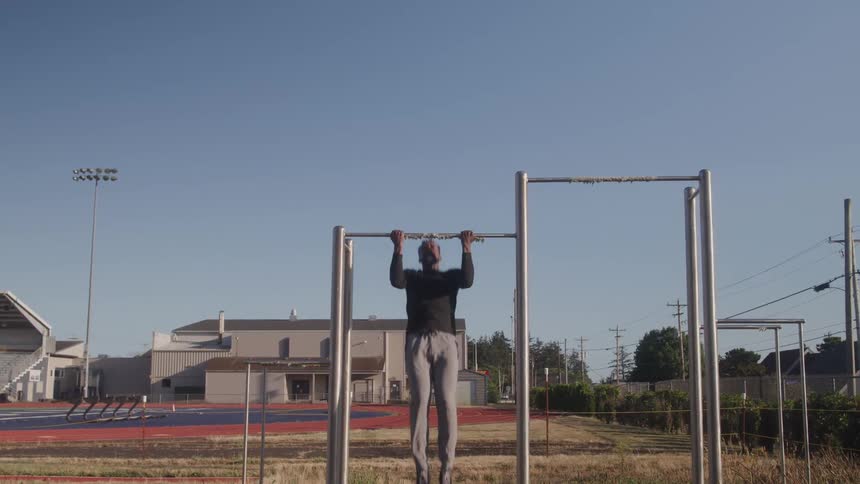 Man outdoors in a sports environment doing free pullup