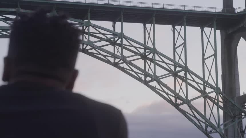 Man with his back in the foreground observing a bridge
