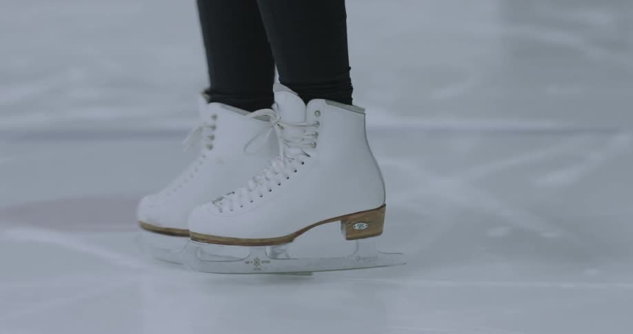 Person ice-skating in a skating rink as seen from the shins down