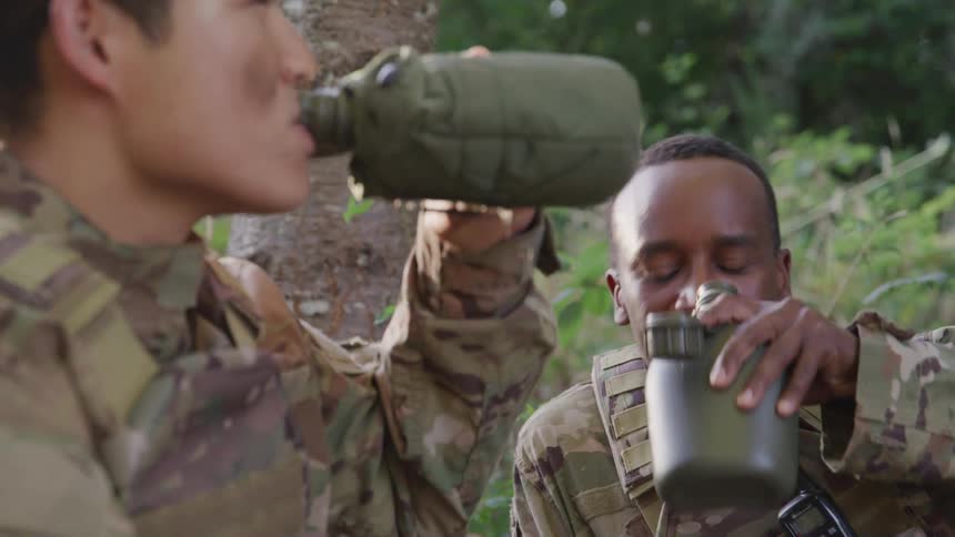 Two soldiers in a jungle talking and drinking