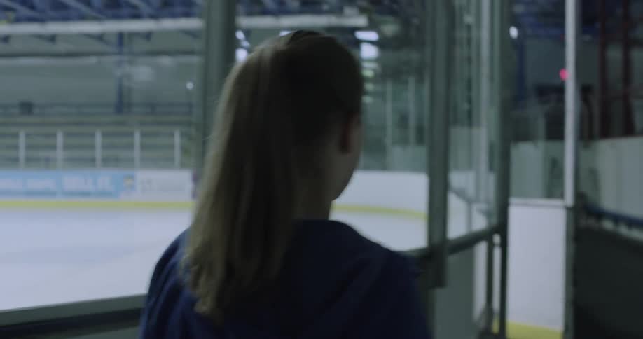 A girl walks towards an indoor ice skating rink