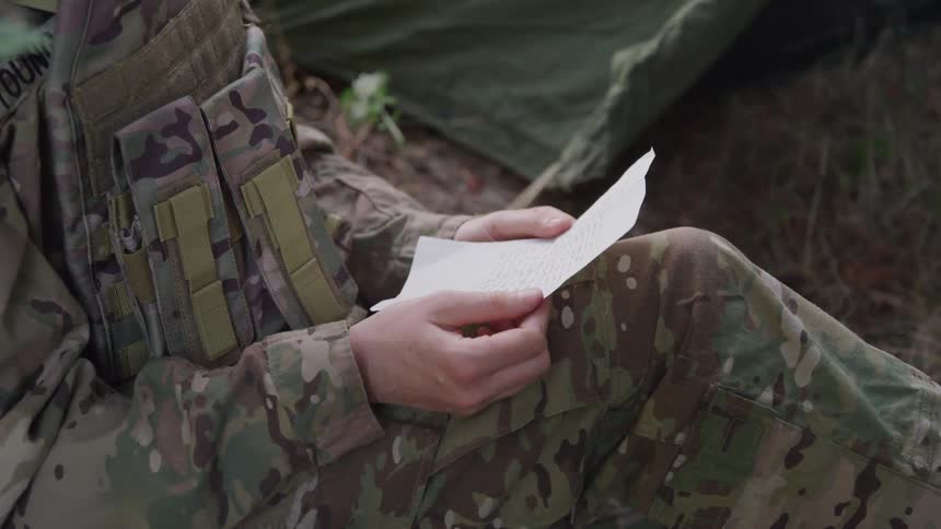 A soldier is reading a note at camp