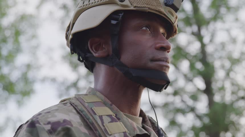 Portrait of a military man outdoors looking up with protective vest and helmet