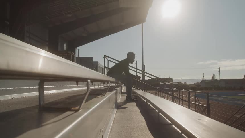 A man is sitting on the bleachers under the sunny sky