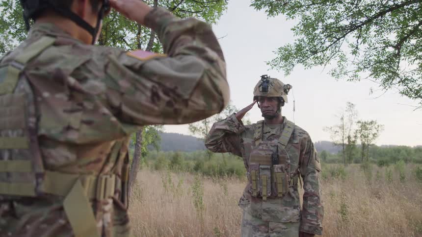 Two soldiers are saluting each other