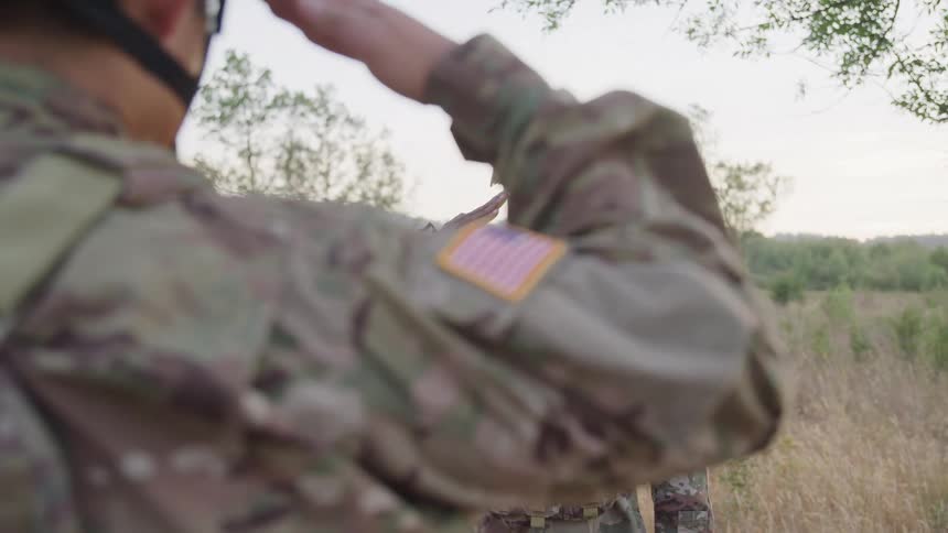 Two soldiers in a forest doing traditional handshake