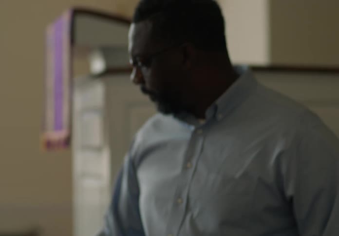 A man is flipping through papers in a binder while standing at a table