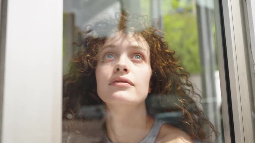 Curly haired woman looking out the window