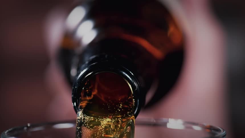 Beer is poured from a dark glass bottle