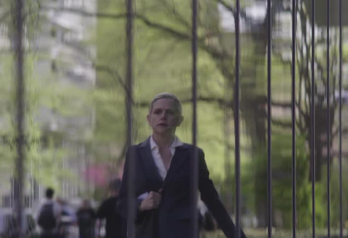 Reflection in a wall of a woman walking on the sidewalk in a hurry