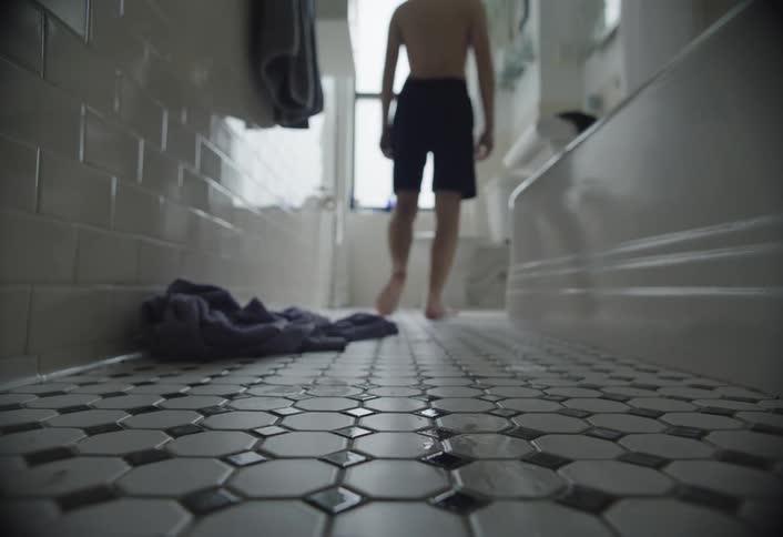 A boy leans on the sink in the bathroom