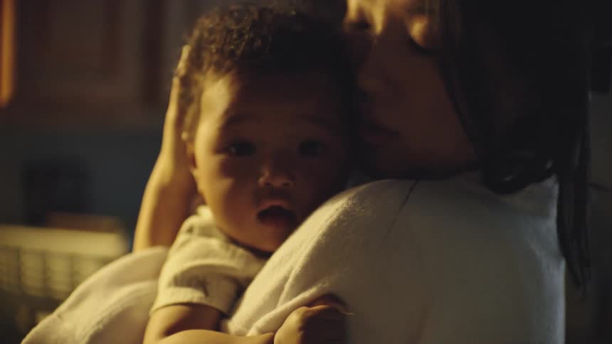 A mother holds her child over her shoulder soothing the baby gently