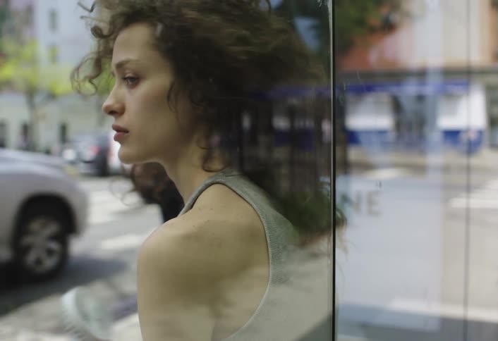 Woman getting up from a chair at an outdoor bus stop in the city