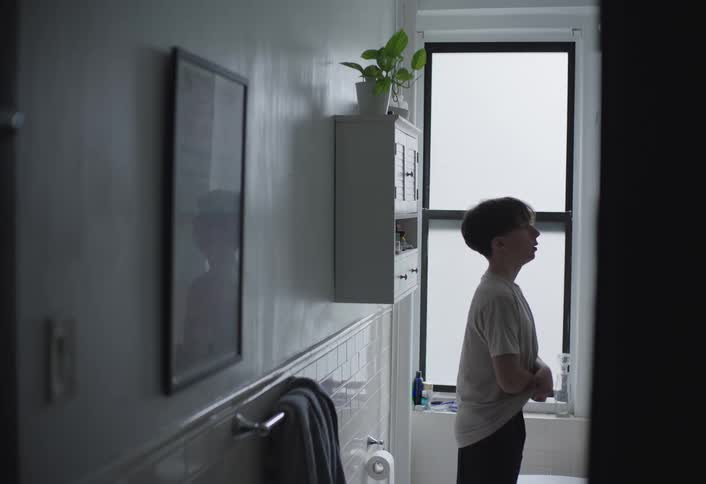 Boy in bathroom taking off his shirt