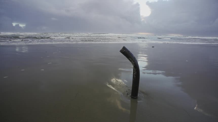 A pole sticking out of the sand