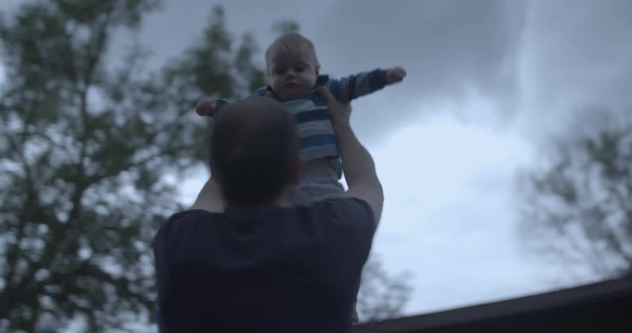 A man lifting a baby up and spinning around