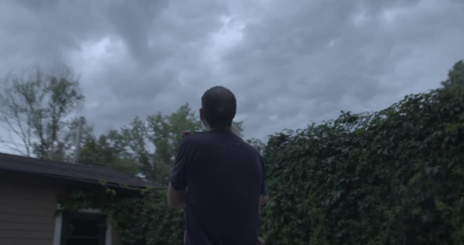 A man is looking at the sky while holding his son