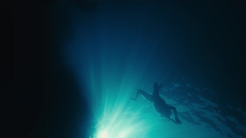 Underwater view and silhouette of a woman swimming
