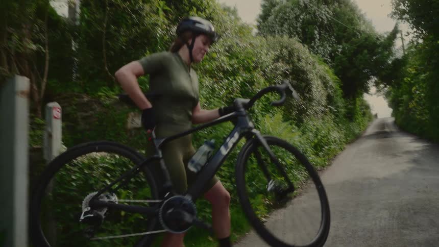 A woman gets on her bike on the trail