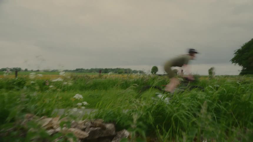 Cyclist riding down a road surrounded by vegetation on a cloudy day