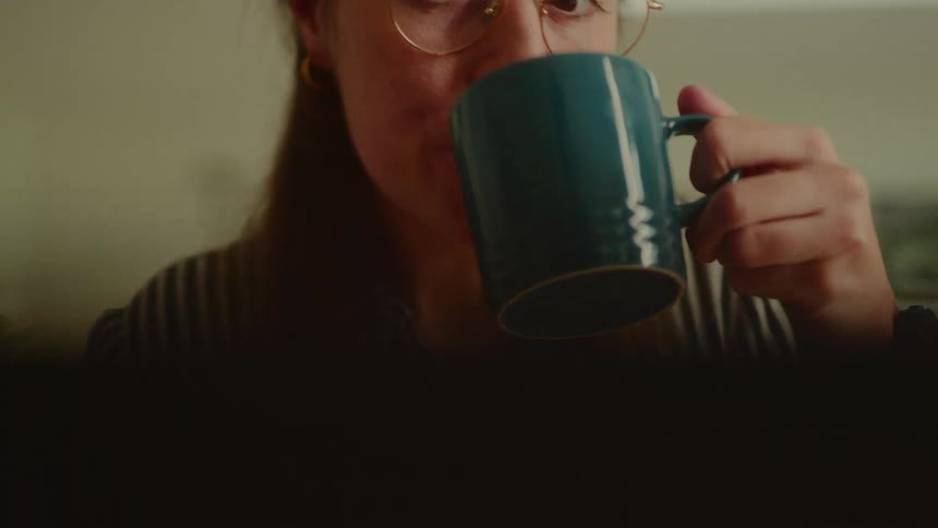 A woman is drinking from her mug