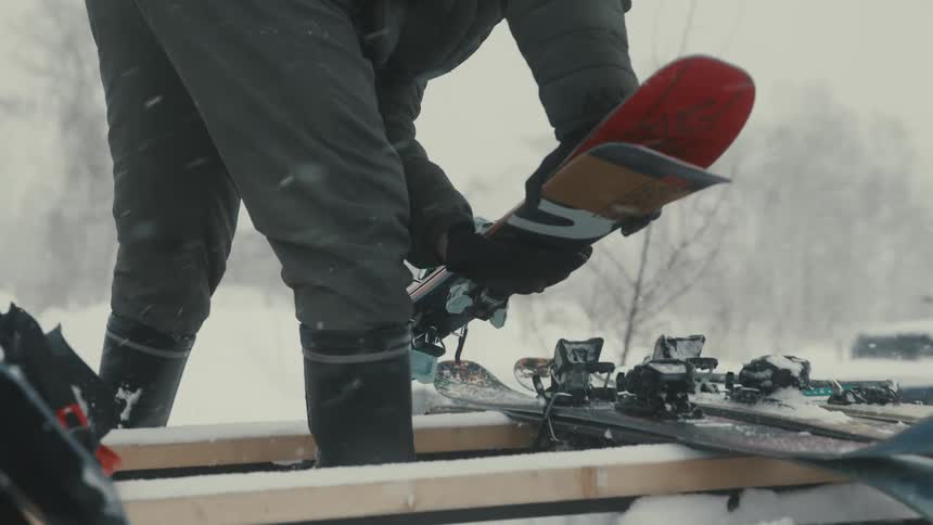 A person is loading skis as it snows