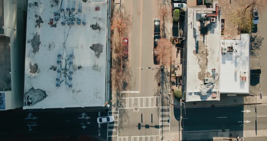 A person walks through a parking lot full of cars toward a building in a city