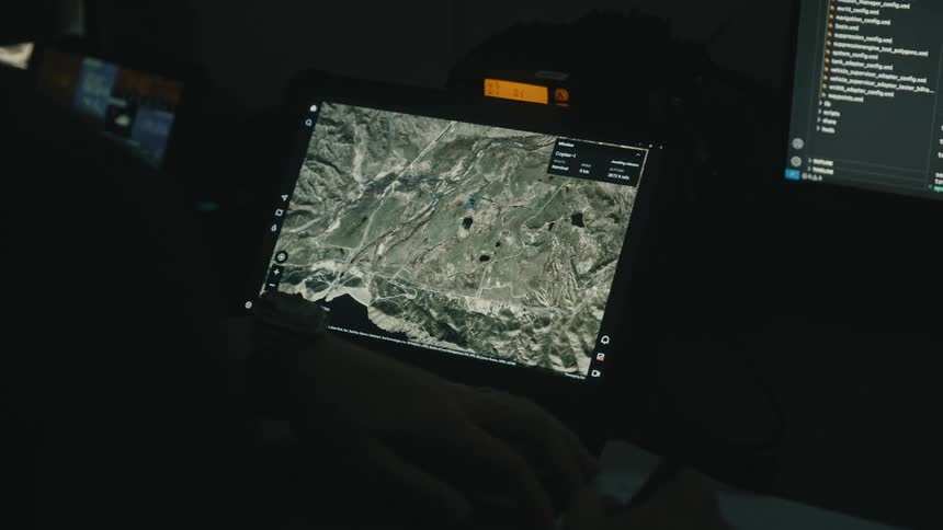 A person writes on a pad while looking at a tablet