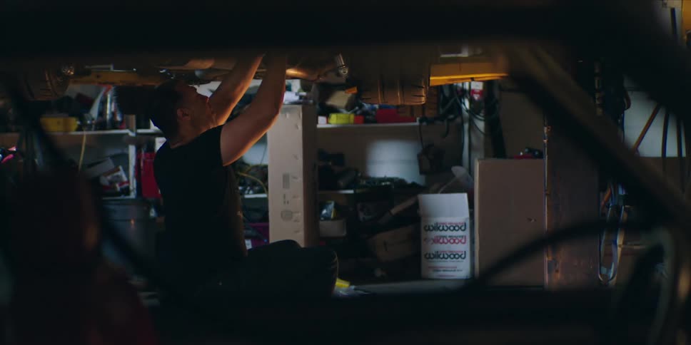 Mechanic sitting under a car working in the workshop