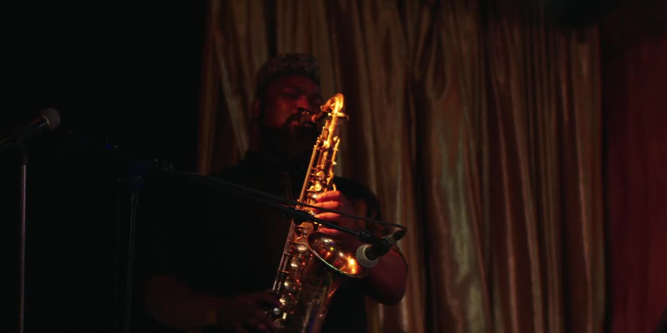The man is playing the saxophone on stage