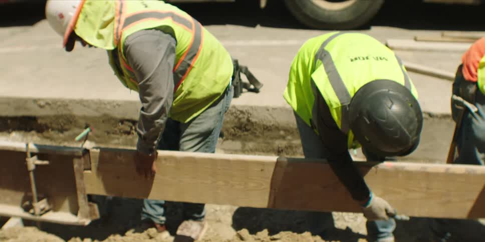 Three construction workers are actively working on a road