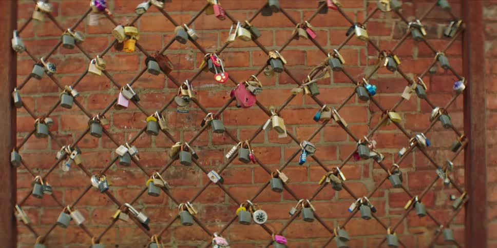 The fence has many small padlocks hanging from it
