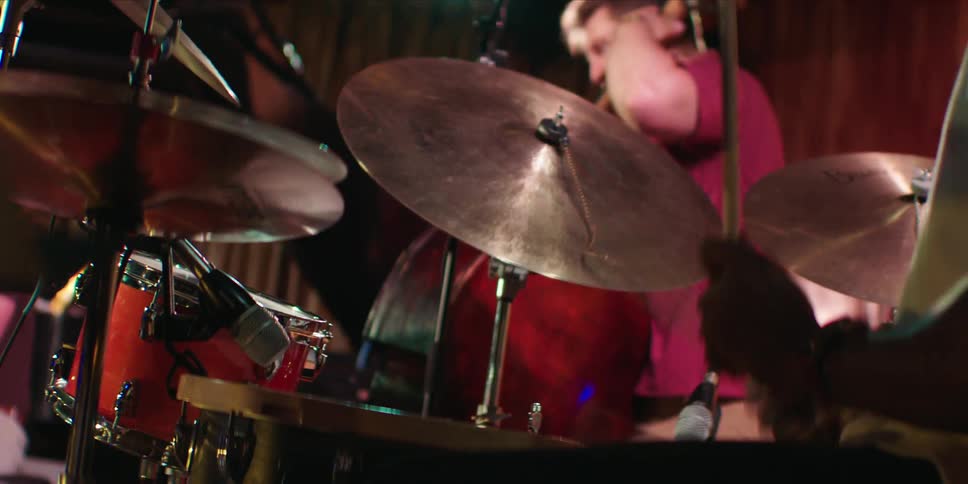 Man playing drums and another on violin in a performance