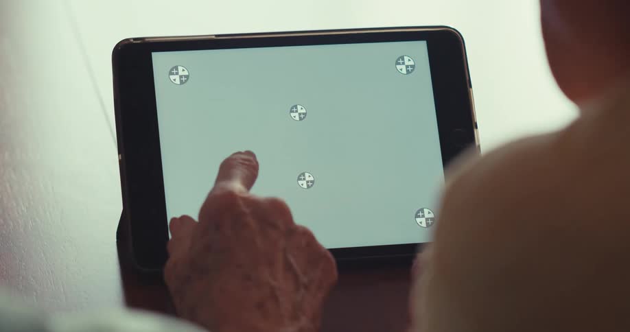 An elderly persons hand touching a tablet screen