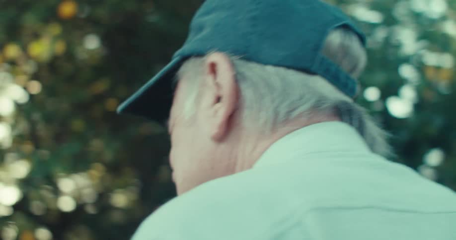 Old man walks in yard smiling and holding a ball