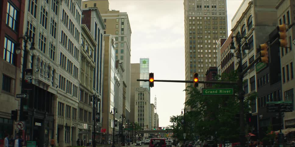 Cars drive downtown in a metropolis while traffic lights change