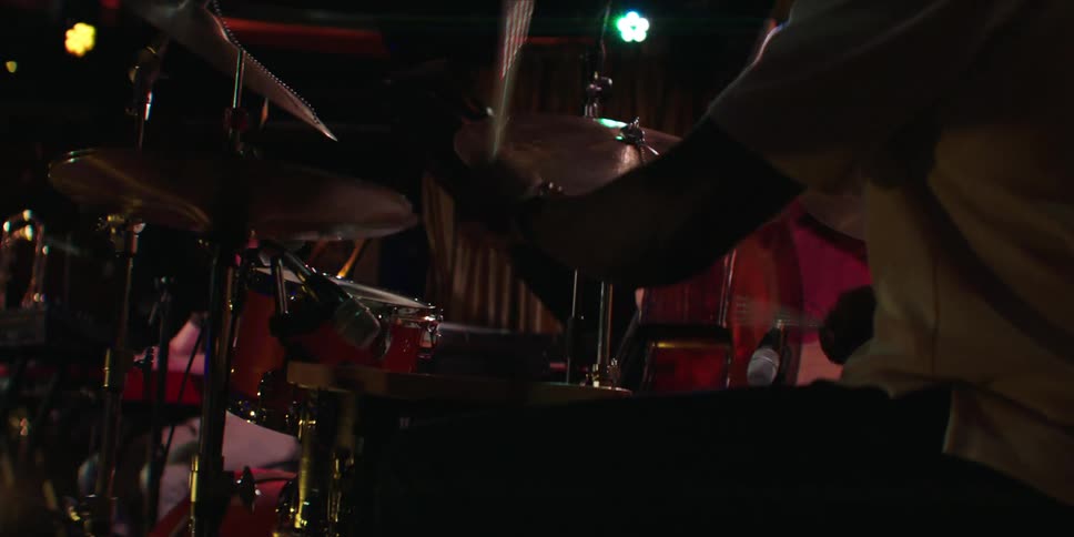 Two musicians perform energetically on stage with drums and guitar during a live event