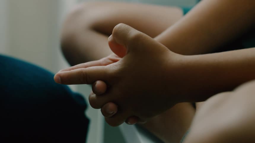 A boy is sitting and pointing his fingers