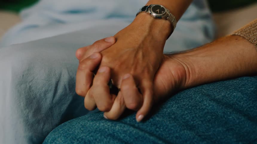 Close up of a couple holding hands while sitting