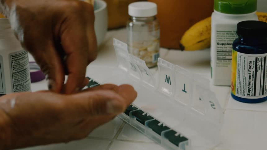 Person allocating vitamins in a weekly plastic container