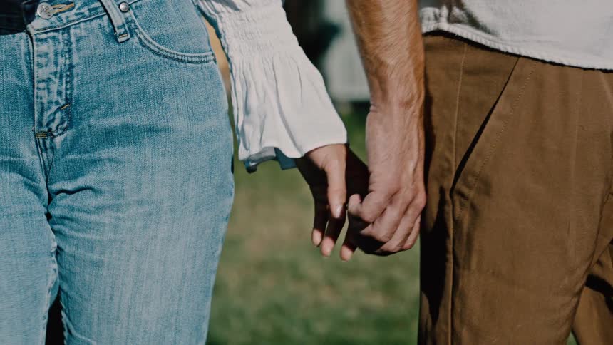 Aman and woman touch hands then walk away