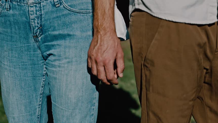 A woman drinks and touches a mans hand