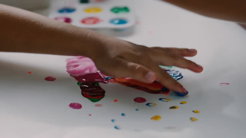 Hands of two children playing with colorful paint