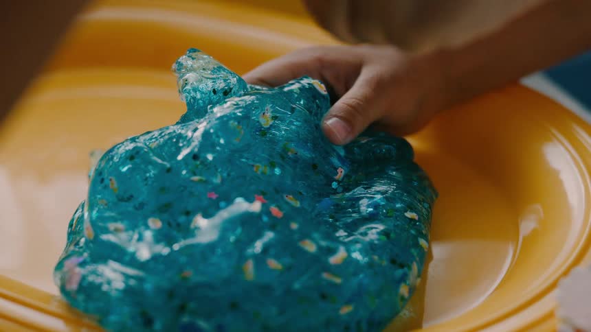 Two children pour glitter on the slime