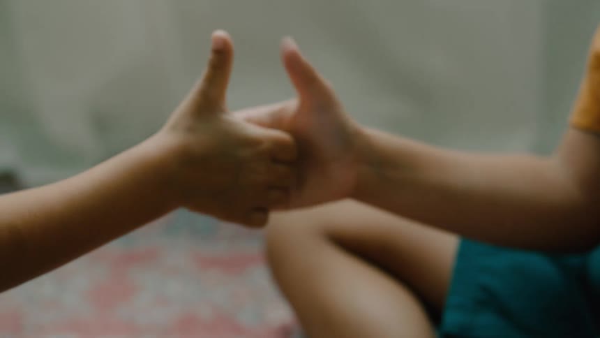 Two childrens hands play a thumb wrestling game